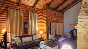 A cozy log cabin interior with a wooden ceiling, a stone wall, a fireplace, and a sofa set. - "The Northern Star" Townhouse @ Snowshoe on Raven Golf Course (Snowshoe)