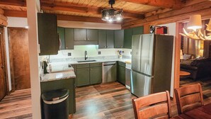 A spacious kitchen with wooden ceiling beams, green cabinets, and modern appliances. - "The Northern Star" Townhouse @ Snowshoe on Raven Golf Course (Snowshoe)