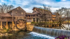 A historic watermill with wooden buildings and a large water wheel. - 🛏️ Knotty Nice | Sleeps 11 in 2BR + Game Room + Hot Tub 🏔️ (Sevierville)