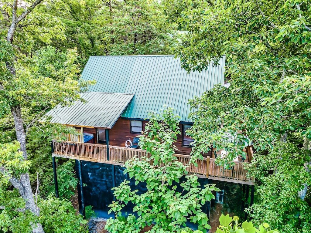 Une cabane dotée d’un toit végétalisé, d’une terrasse en bois et entourée d’une végétation luxuriante.