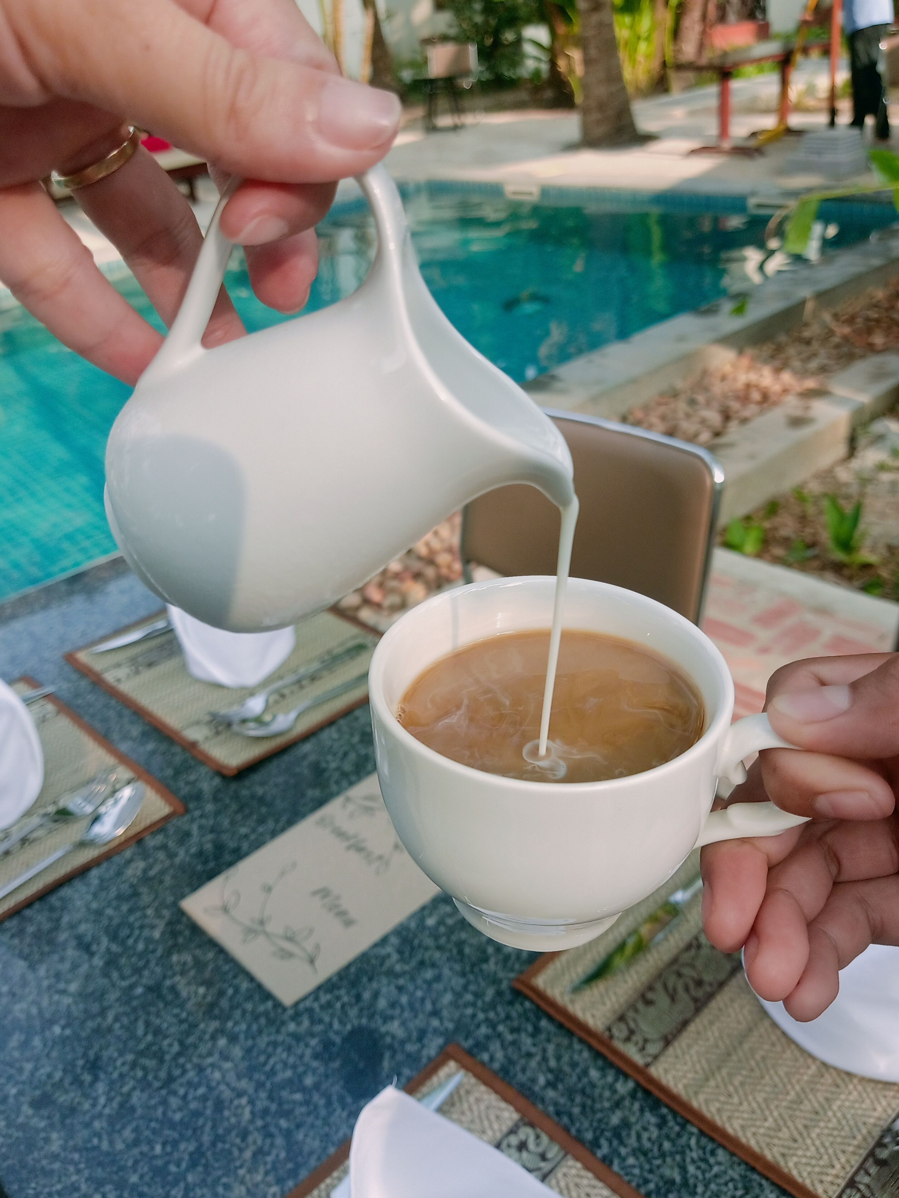 A person pouring milk into a cup of coffee.