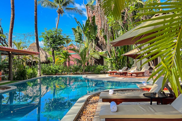 Una piscina al aire libre, sombrillas, sillones reclinables de piscina