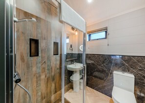 A modern bathroom with a shower, sink, and toilet, featuring wooden and marble walls.