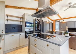 A modern kitchen with a central island, built-in oven, and a ceiling fan.