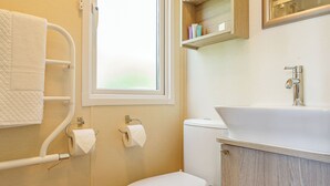 A bathroom with a toilet, a sink, a towel rack, and a window. - 2 bedroom accommodation in Sandymouth Bay, Bude (Sandymouth Bay, Bude)