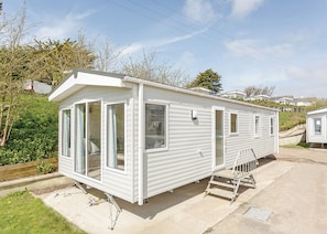 A white mobile home with large windows, a door, and a small porch. - 2 bedroom accommodation in Sandymouth Bay, Bude (Sandymouth Bay, Bude)