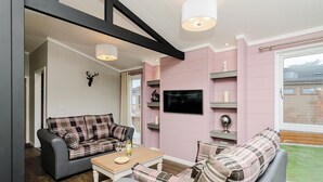 Un salon moderne avec un canapé gris, un canapé à carreaux, une table basse en bois et un téléviseur fixé au mur.