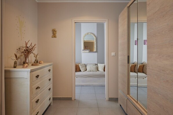 A hallway leading to a bedroom with a bed, a dresser, a mirror, and a wall with a decorative piece. - CHARMING APARTMENT BY THE HARBOR, JUST A 5-MINUTE WALK FROM THE BEACHES (Propriano)