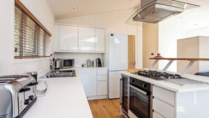 A modern kitchen with white cabinetry, a built-in microwave, a gas stove, and a toaster.