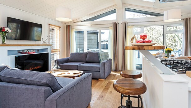 A modern living room with a fireplace, sofa, and bar area with stools.