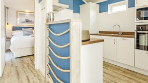 A compact kitchen with white cabinets, a wooden countertop, and a built-in oven.