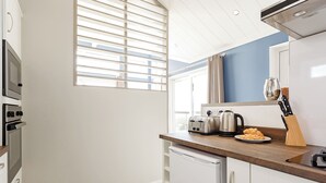A compact kitchen with a built-in oven, a toaster, a kettle, and a knife block on the counter.