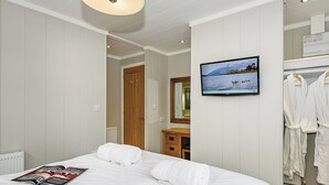 Ein Hotelzimmer mit Bett, Fernseher, Spiegel und Kleiderschrank.