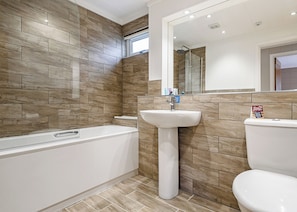 Een badkamer met een bad, wastafel en toilet.