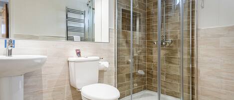 A bathroom with a glass-enclosed shower, a toilet, and a sink.