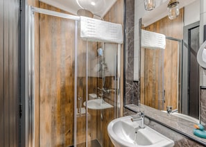 Un baño moderno con pared de madera, cabina de ducha de vidrio, lavabo y espejo.