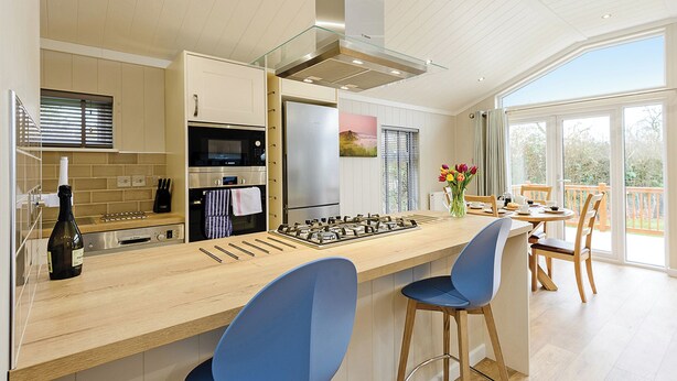 A modern kitchen with a central island, bar stools, and a dining area with a view. - 2 bedroom accommodation in Holton Heath (Holton Heath)