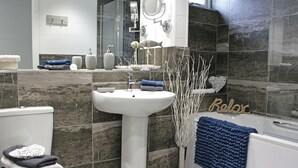 A bathroom with a white sink, a toilet, a bathtub, and a mirror.