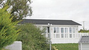 A single-story house with a white exterior, a grey roof, and a white fence.