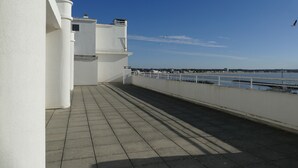 A balcony with a view of the sea and a distant bridge.