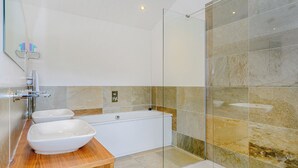 Une salle de bain moderne avec une baignoire, un grand lavabo blanc et une cabine de douche en verre.