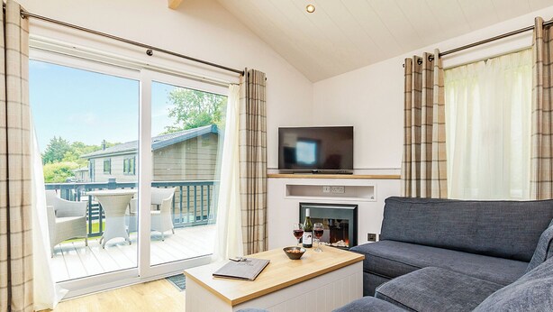 Un salon moderne comprenant un canapé, un téléviseur, une cheminée et un balcon am énagé avec du mobilier d’extérieur.