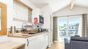 Une cuisine moderne avec des meubles blancs, un plan de travail en bois et une vue sur l’extérieur.