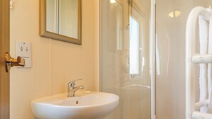 Une salle de bain équipée d’un lavabo, d’un miroir et d’une douche à parois en verre.