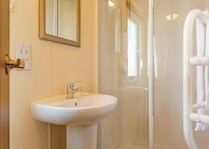 A bathroom with a sink, mirror, and glass shower enclosure.