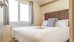 Un lit bien fait, avec des oreillers, une tasse de café et des croissants sur la table de chevet, dans une chambre d'hôtel.