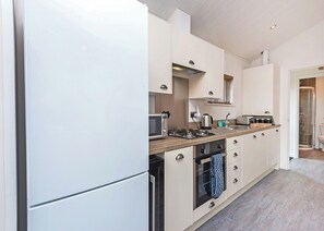 Une cuisine moderne équipée d’un four encastré, d’un four à micro-ondes et d’une cuisinière à gaz.