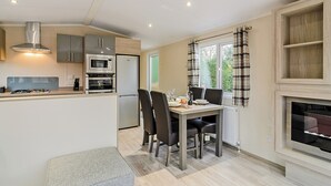 A compact kitchen with modern appliances, a dining area with a table and chairs, and a fireplace.
