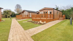 A two-story wooden house with a paved walkway and a small garden area.