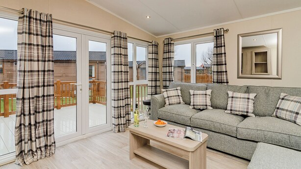 A living room with a sofa, a coffee table, and a sliding glass door leading to a deck.
