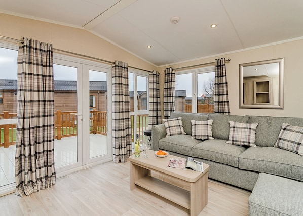 A living room with a sofa, a coffee table, and a sliding glass door leading to a deck. - 1 bedroom accommodation in Canterbury (Canterbury)