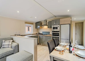 A compact kitchen with modern appliances, a dining area with a table set for two, and a sofa in the adjacent living area. - 1 bedroom accommodation in Canterbury (Canterbury)