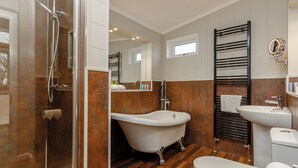 A modern bathroom with a glass-enclosed shower, a freestanding bathtub, a toilet, and a sink. - This charming one-bedroom lodge boasts all the home comforts you need. (Cheddar)
