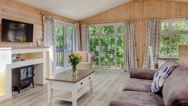 A cozy room with a TV, sofa, wooden walls, large windows, and a skylight.