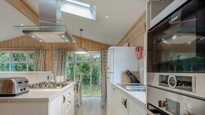 A modern kitchen with a gas stove, a Bosch oven, and a window with a view of greenery.