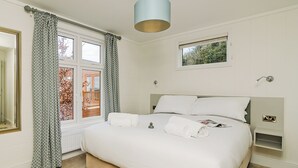 A bedroom with a bed, curtains, a window, a bedside table, and a ceiling light fixture. - 2 bedroom accommodation in Canterbury (Canterbury)