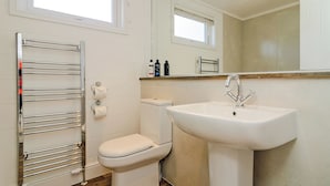 A bathroom with a toilet, a sink, a towel rack, and a mirror. - 2 bedroom accommodation in Canterbury (Canterbury)