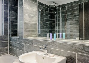 Ein modernes Badezimmer mit großem Spiegel, Dusche und Waschbecken.