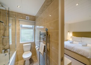 A modern bathroom with a glass shower enclosure, a toilet, and a built-in towel rack.