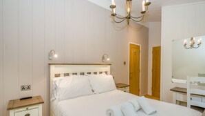 Quarto com cama, mesas de cabeceira, espelho e lustre.