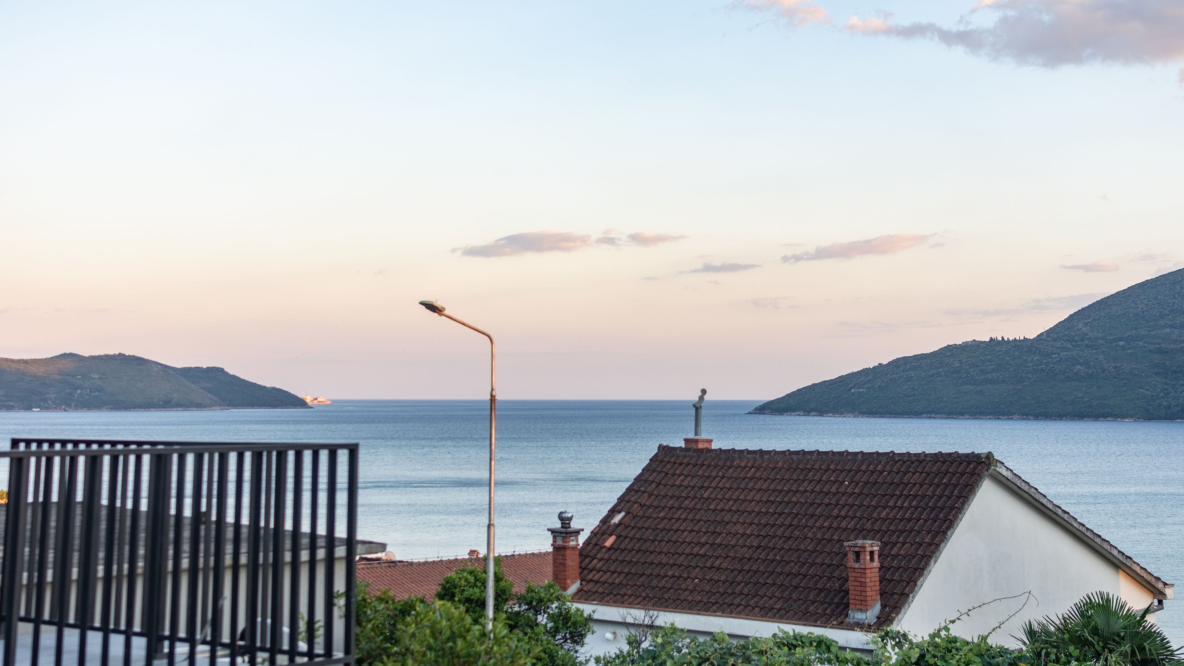 A coastal view with a house, a street lamp, and a distant island.