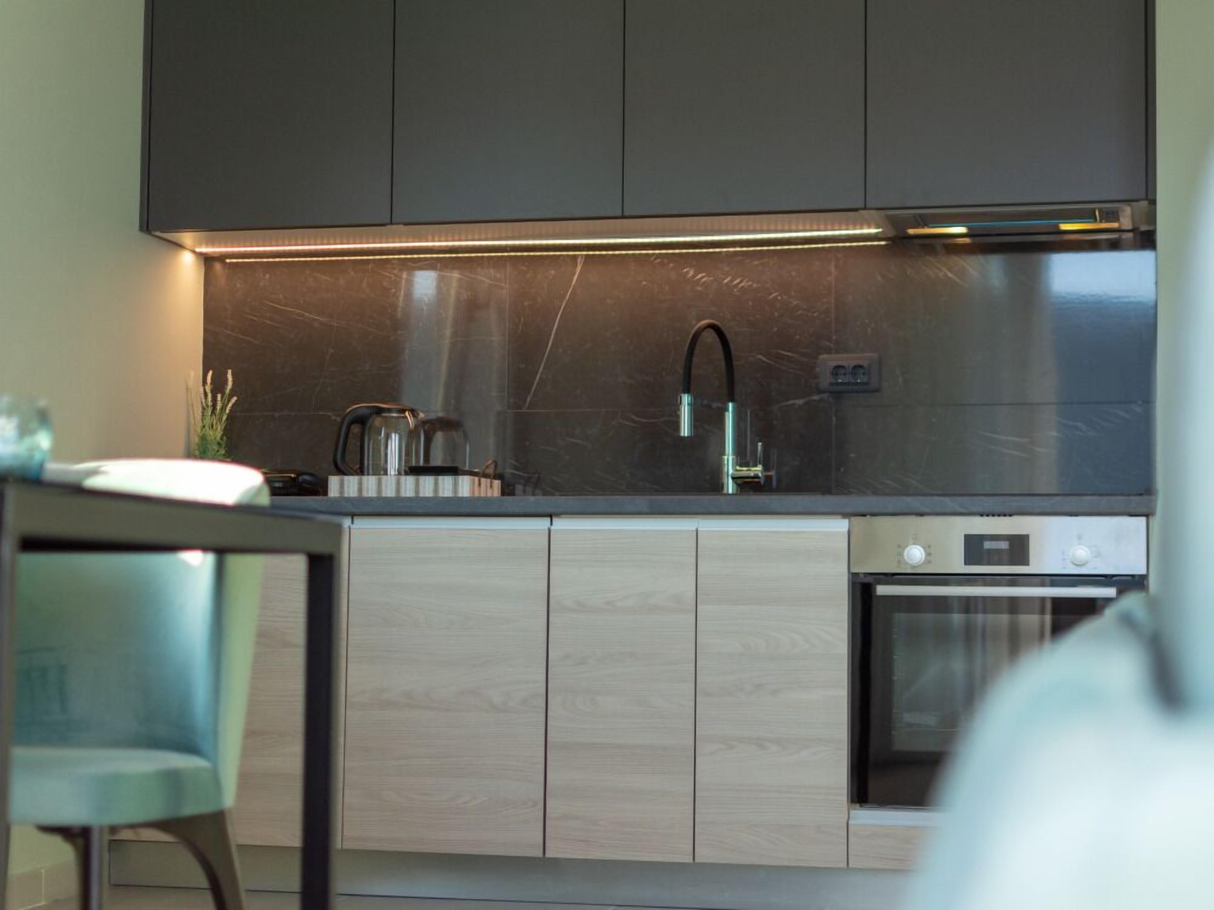 A modern kitchen with dark cabinets, a stainless steel sink, and a built-in oven.