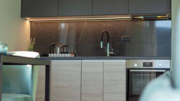 A modern kitchen with dark cabinets, a stainless steel sink, and a built-in oven.