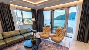 A modern living room with a sofa, two armchairs, a coffee table, and a view of the sea through large windows. - Hotel Krušo (Herceg Novi)