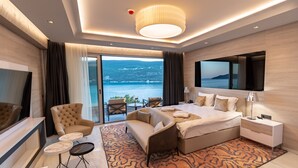 A modern hotel room with a large bed, a TV, a seating area with a view of the sea, and a balcony. - Hotel Krušo (Herceg Novi)