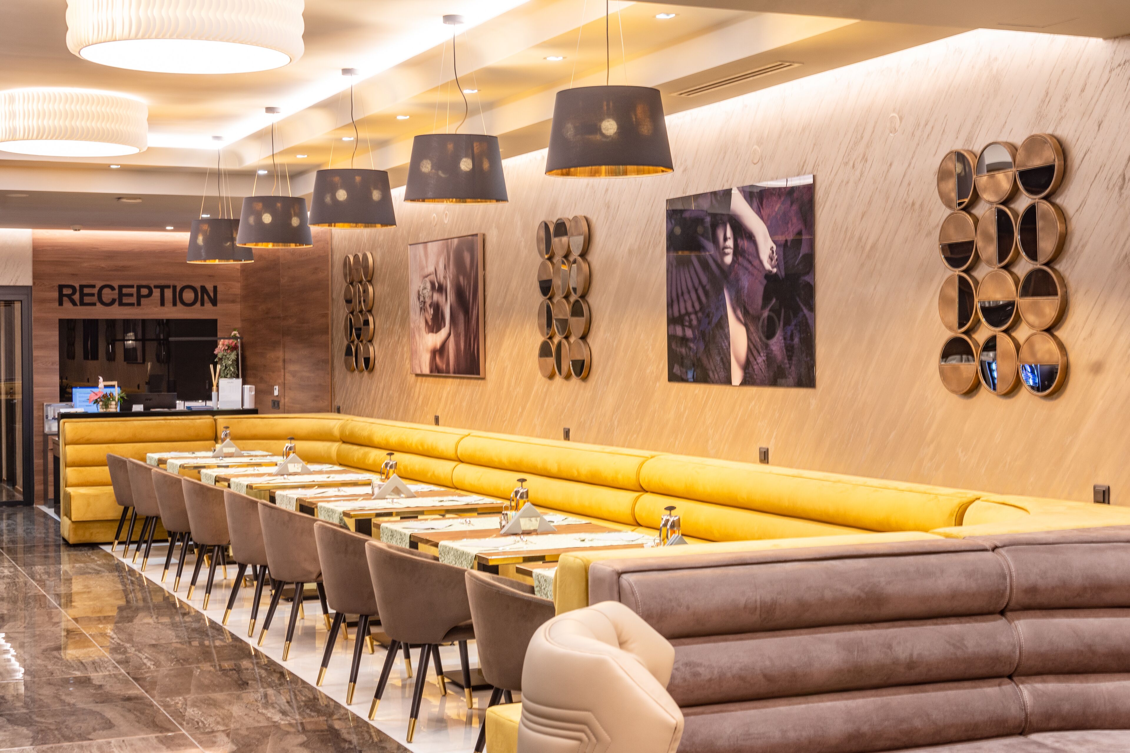 A modern restaurant with a reception area, yellow booths, and contemporary decor.